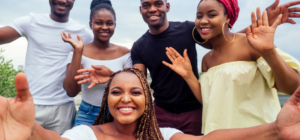 group of five friends female and male taking selfie on camera smartphone and having fun outdoors lifestyle near lake